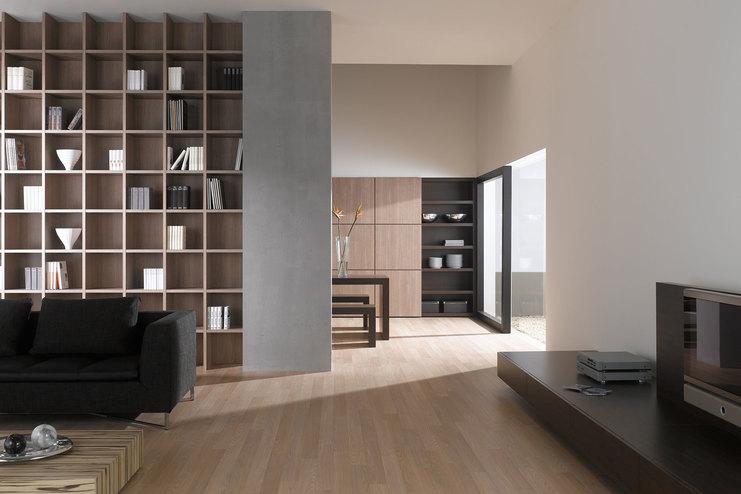 Offene Wohnraumimpression mit Einbauregal für Bücher und Dekoration in Trennwand mit hellem Holzboden